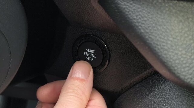 Close up of person pressing engine start button inside car, starting vehicle ignition, modern keyless system, driver hand action, transportation technology, interior detail scene.
