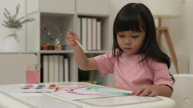 happy preschool child girl painting with watercolor on paper at home