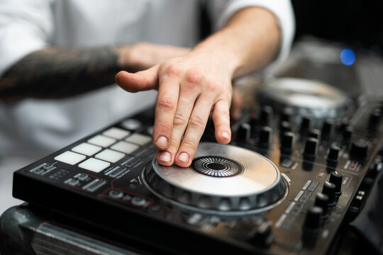 Close-up of DJ hands mixing music on a professional controller