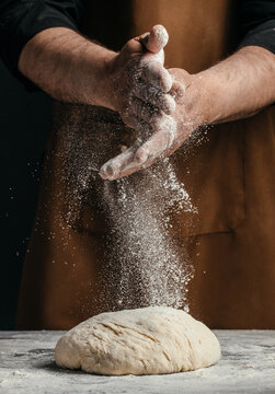 Baker clapping hands with flour dust over dough, bread making action close up