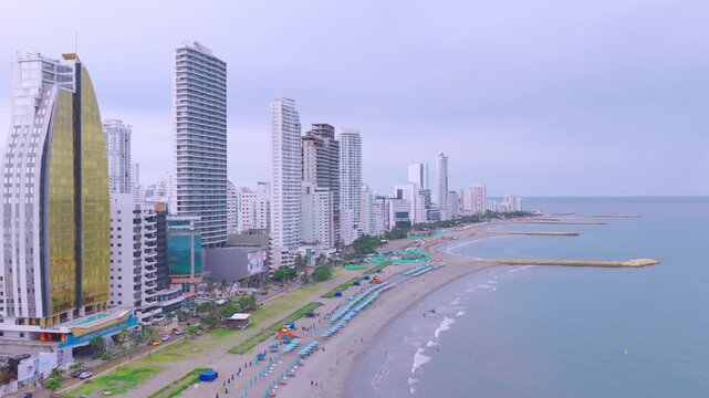 Aerial view of Bocagrande in Cartagena, Colombia, featuring beachfront hotels on one side and the Caribbean Sea on the other. Daytime coastal scene showing urban skyline and sandy beach.