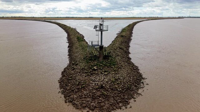 Aerial view of Trent Falls confluence with a navigation beacon and stone breakwaters under an overcast sky in Goole, United Kingdom.