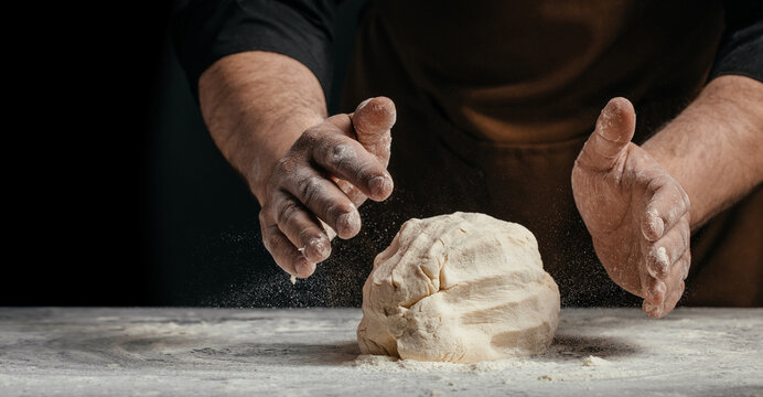 Baker hands shaping dough with flour dust on dark background artisan bread making concept