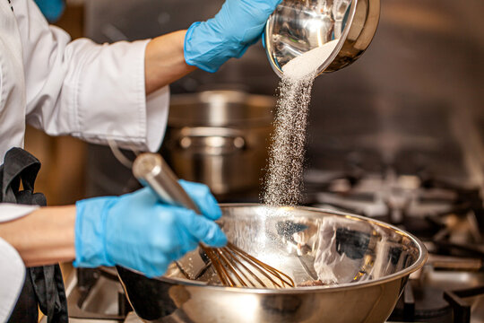 Chef adding sugar into bowl while mixing ingredients