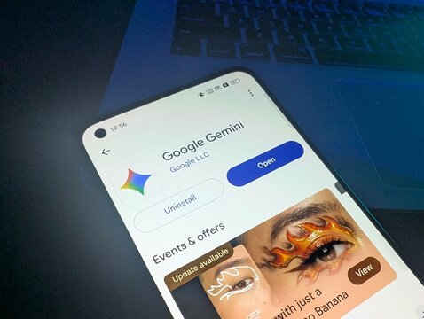 Smartphone screen displaying Google Gemini app listing page on Google Play Store with dark laptop background