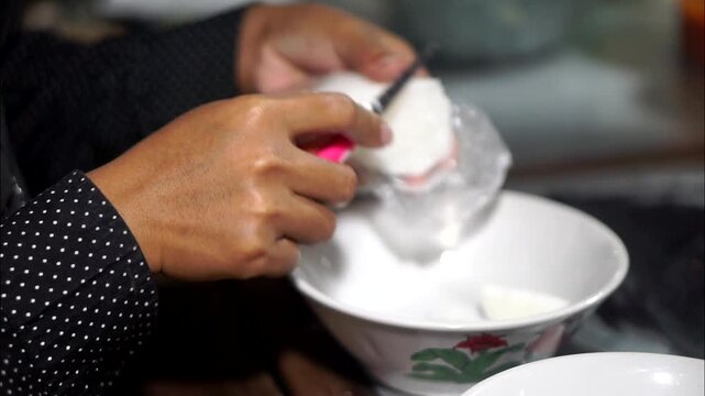 The hands of street vendors selling Indonesian specialties prepare soto lontong in bowls using simple and quick techniques.