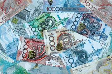 Fototapeta premium Kazakhstani tenge money banknotes pile on table. Kazakhstan bills of KZT currency close up
