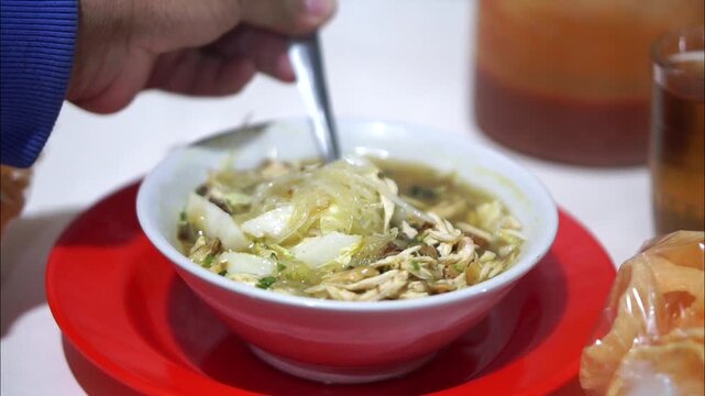 A bowl of hot soto lontong with rising steam tempting the customer while being enjoyed
