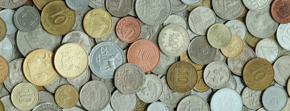 Pile of global currencies, various coin types visible up close. Different nations money together