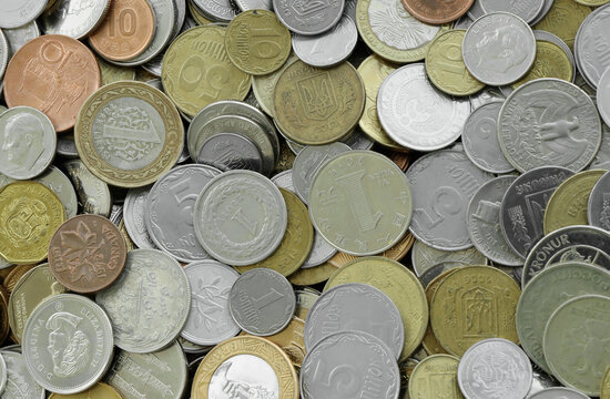 Top view of assorted coins, numerous world currencies together. Shiny metal pieces in mound