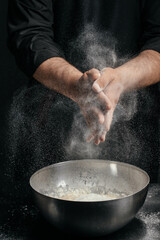 Fototapeta premium Chef clapping hands with flour explosion over bowl dramatic baking action shot