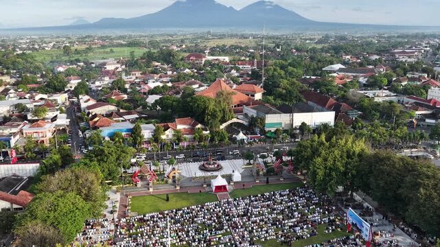 Aerial view of a large crowd of people gathered for prayer in the town square surrounded by trees and buildings Klaten, Jawa Tengah, Indonesia.