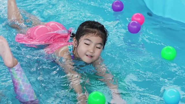 slow motion of preschool child girl playing in portable swimming pool in backyard at home