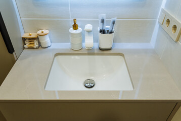 Fototapeta premium Cosmetic Area With Essential Accessories. Streamlined Wash Basin With Grooming Essentials Displayed Neatly. Tidy Personal Care Station Featuring Cleaning Products And Lighting Accents
