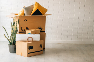 Stack of cardboard moving boxes with truck and house icons, bubble wrap, and packing tape on top,...