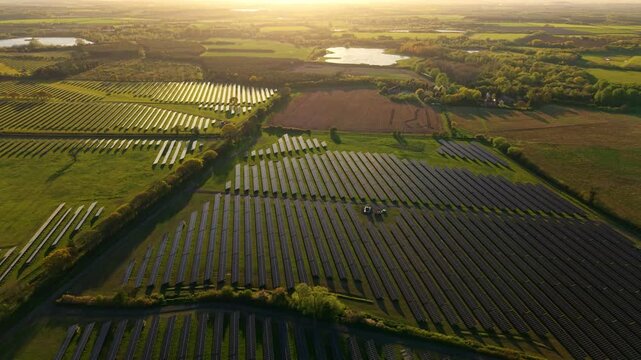 Aerial view of the Tiln Battery Energy Storage System solar farm with rows of panels across green fields at sunset in Retford, England, United Kingdom.