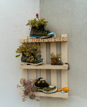 A charming herbarium of flowers made from old shoes hangs on the wall of a trullo in Alberobello with the inscription "Gino's shoes"