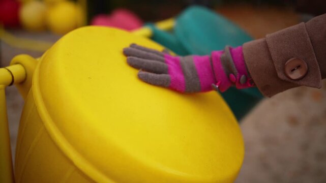 Woman in gloves knocking on toy drum on playground