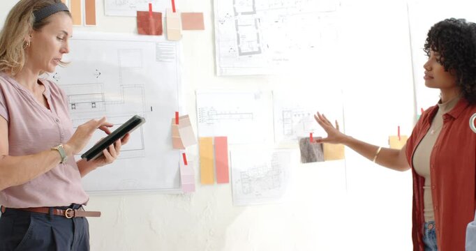 Diverse female team reviewing board in studio, tablet user entering, tapping, choosing, copy space