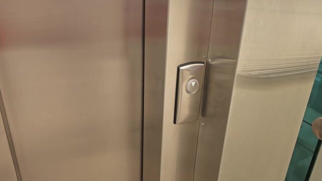 Someone presses the button to call the elevator in a modern building lobby