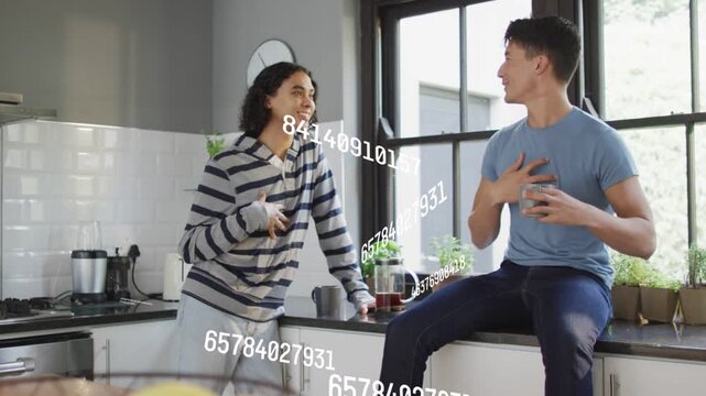 Right person extending phone and showing screen, left laughing in kitchen with moving data stream