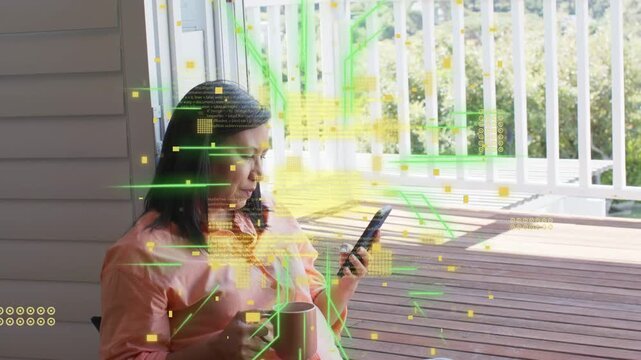 Woman sitting on deck holding mug, tapping smartphone, activating green code streams for tech demo