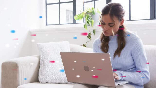 Woman opening laptop and toggling phone on sofa, entering remote work data while particles overlay