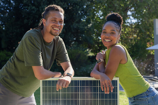 African American couple leaning on solar panel, smiling in sunny backyard with wristwatches