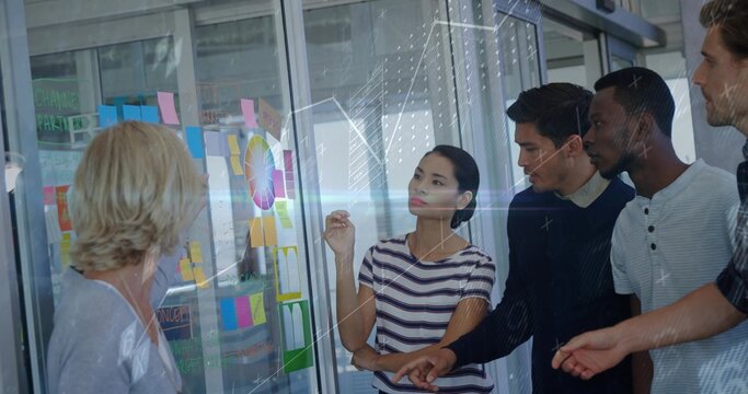 Discussing five coworkers in striped shirt pointing at glass planning wall, with Post-it notes