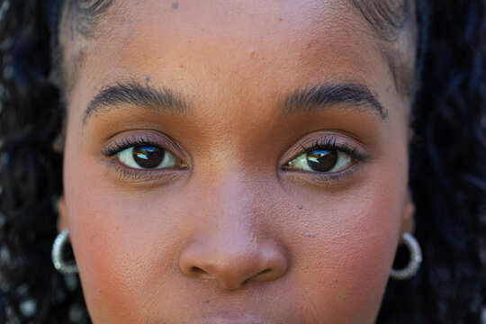 African woman looking directly at camera in close-up showing hoop earrings, mascara, skin