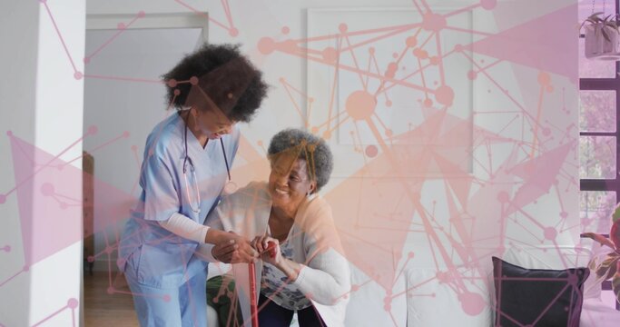 Supporting caregiver in scrubs holding senior wrist while guiding red cane at home with stethoscope