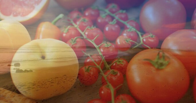 Showing double-exposed fruit blending on wood tabletop, with vine of cherry tomatoes and sunset sea