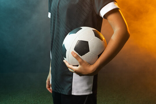 African American woman holding b and w ball standing on turf in black jersey, shorts amid colored sm