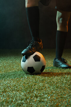 African American woman balancing black cleat on soccer ball while wearing knee-high socks on turf