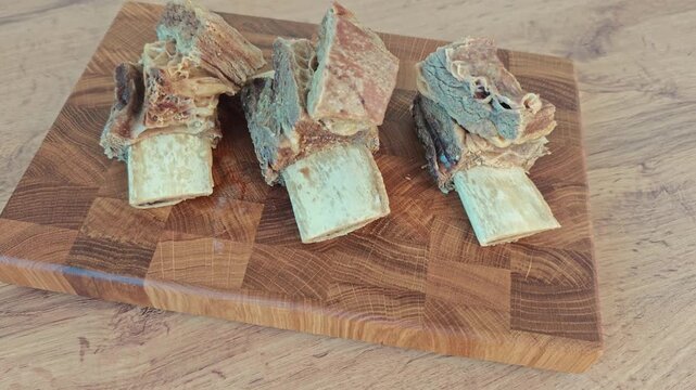pieces of delicious boiled meat on the bone are laid out on an oak chopping board, cooking borscht