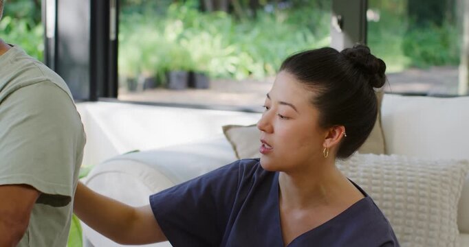 Asian woman reaching, touching man's back seeking attention on sofa near glass doors, man replying