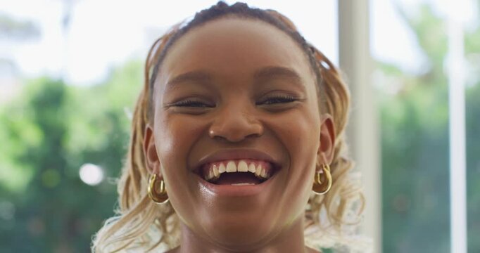 African American woman smiling, widening into laugh responding to cue in studio with gold hoops