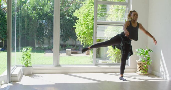 Woman right edge starting on left leg sweater practicing arabesque for balance by glass, copy space