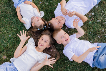 Fototapeta premium happy children lying on the lawn in summer and catching soap bubbles, top view. international children's day