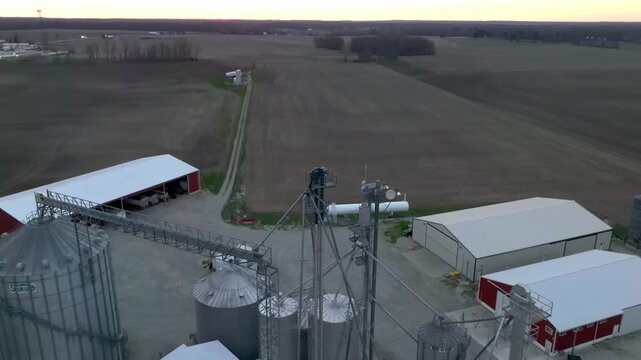 Aerial view of grain silos and farm buildings surrounded by vast agricultural fields at dusk in Wilmington, Ohio, United States.