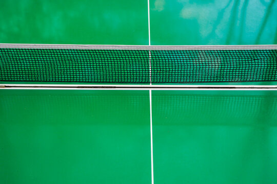 Table tennis net close-up on green ping pong table with white lines
