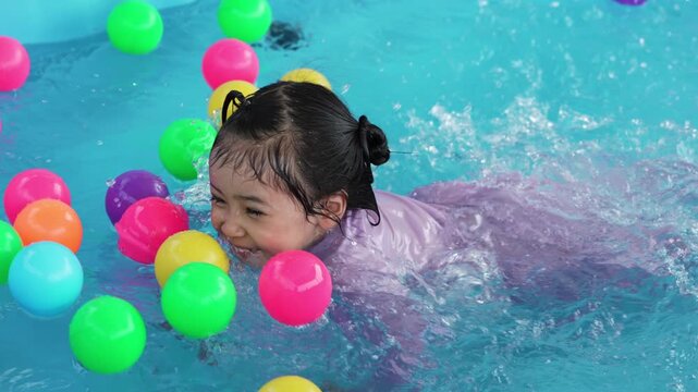 slow motion of happy preschool child girl playing together with her sister in outdoor portable swimming pool in backyard at home