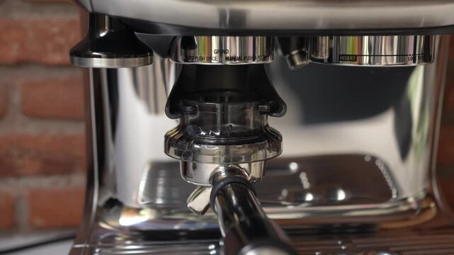 Close up of espresso extraction process in coffee machine. Portafilter brewing fresh coffee shot in cafe with professional equipment