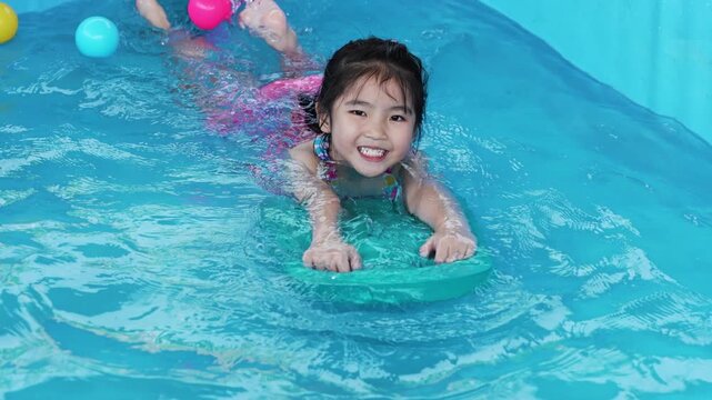 slow motion of preschool child girl playing in portable swimming pool in backyard at home
