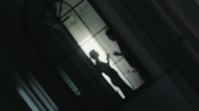 Silhouettes of a quarrelling couple in a dark room, reflected in a mirror. Aggressive gestures and conflict between partners, a concept of relationship problems and family tension. High quality 4k