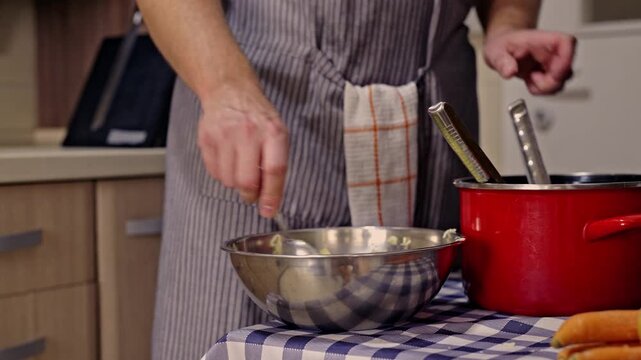 Capturing the art of cooking, a person in an apron mashes and adds pepper to potatoes in a bowl. The scene conveys a sense of homemade goodness and culinary skill.