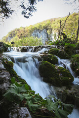Obraz premium Small waterfall flowing over mossy rocks in forest landscape