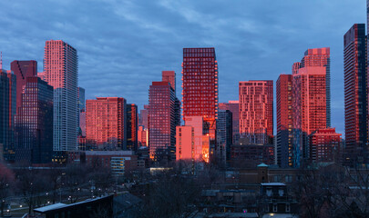 Fototapeta premium Newly completed condos and other downtown Toronto buildings glow fiery red in the dawn sunlight.