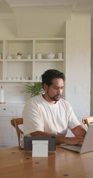 Vertical video: African American man starting remote work, typing on laptop, checking label maker