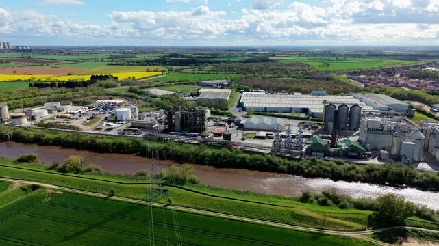 Aerial view of the Sedamyl Industrial Factory complex situated along the River Ouse with surrounding green fields under a cloudy sky in Selby, England, United Kingdom.